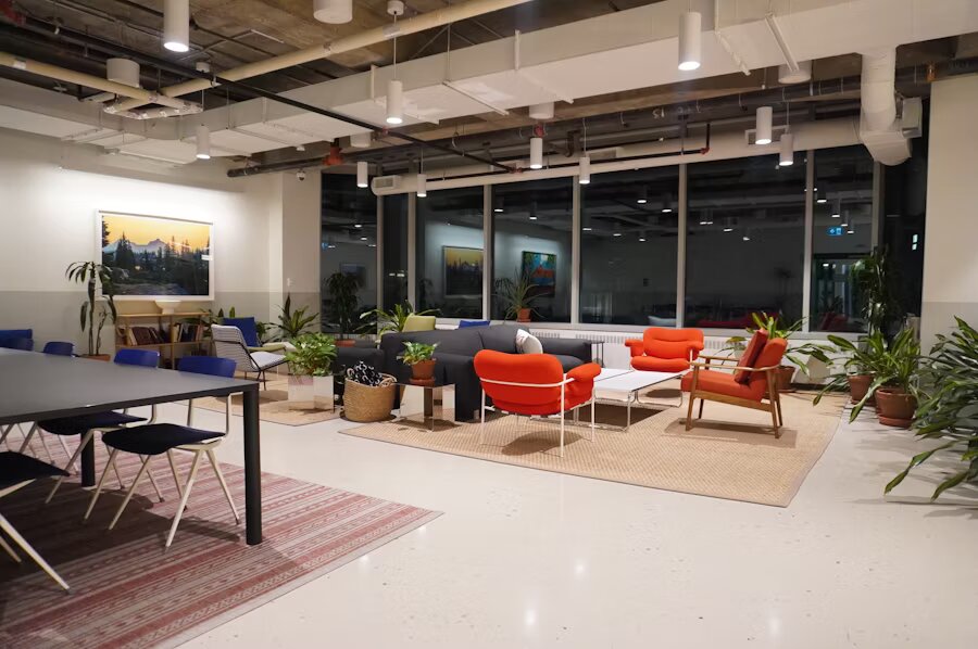 Espacio de coworking con sillones naranjas, sofás, plantas y mobiliario relajado para reuniones informales